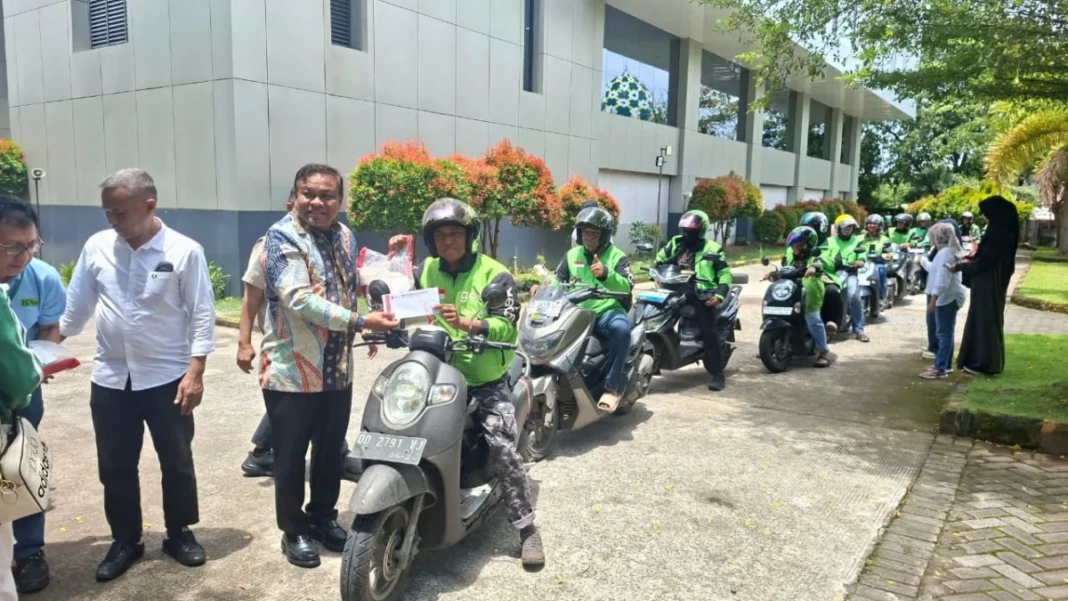 Ketua Panitia Baksos Andi Fahsar M. Padjalangi atau akrab disapa Puang Baso menyalurkan beras kepada salah satu driver ojek online.