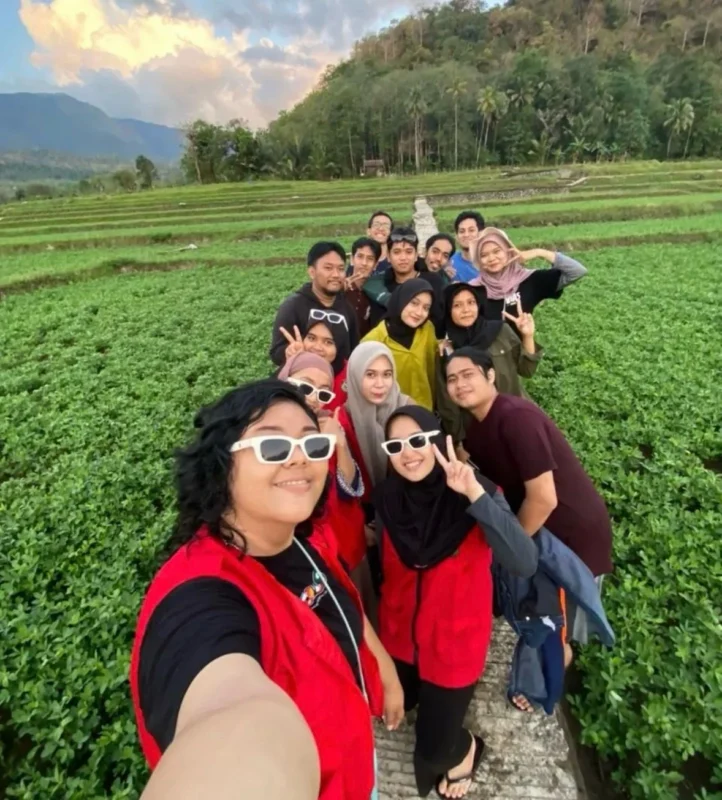 Mahasiswa KKN Unhas berjalan menuju Celebes Canyon dengan pemandangan hamparan sawah hijau