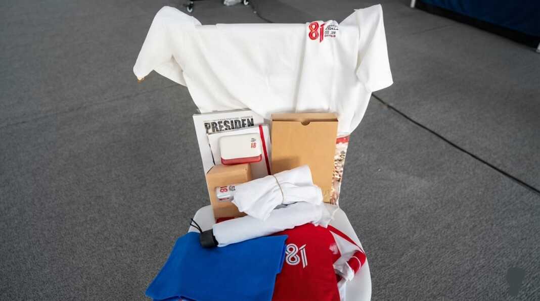 Tampilan isi goodie bag tamu Upacara HUT ke-81 RI di Istana Merdeka, Jakarta, yang memuat buku Presiden Solusi, buku kerja pemerintahan, tumbler, kaos, handuk, serta permainan tradisional seperti kelereng dan karet gelang.
