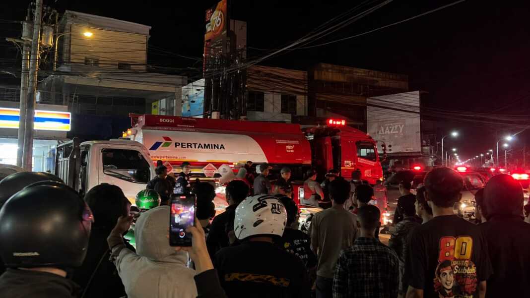 Armada pemadam kebakaran dan mobil tangki bersiaga di depan kantor distribusi Yakult di Poros Pallangga, Gowa, saat proses pemadaman berlangsung pada Sabtu malam, 15 Agustus 2026.