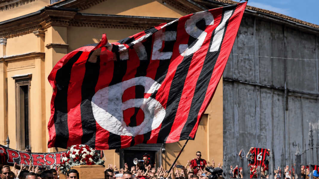 Bendera merah-hitam bertuliskan Baresi 6 berkibar di atas kerumunan pelayat saat pemakaman Franco Baresi di Milan, Italia.