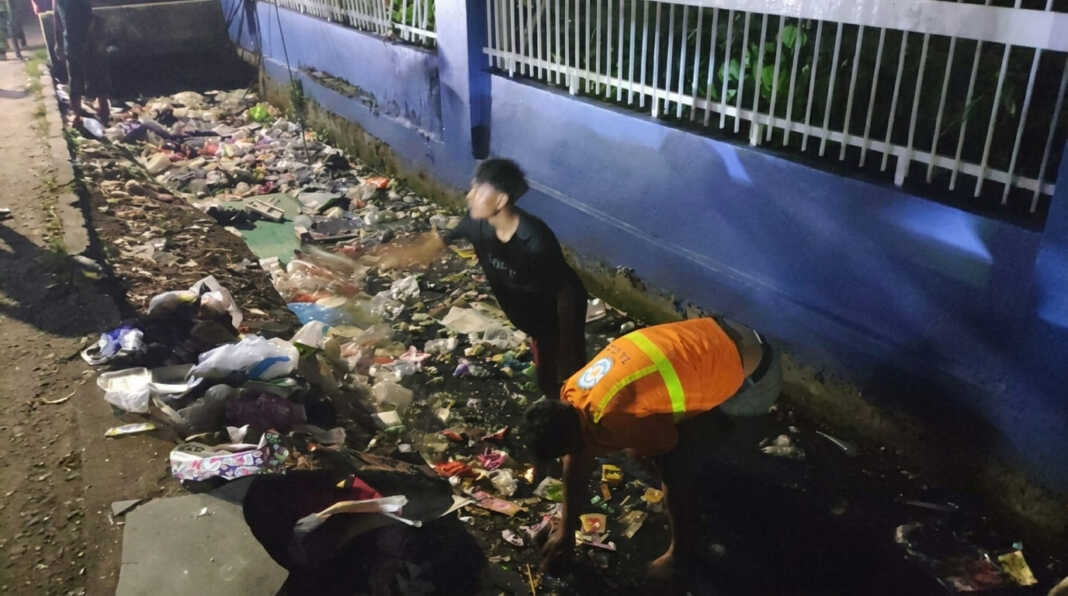 Petugas membersihkan sampah di drainase Jalan Mallengkeri depan Kompleks TVRI Makassar.