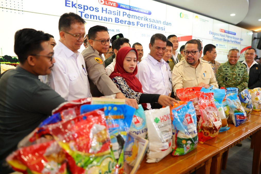 Menteri Pertanian Andi Amran Sulaiman bersama jajaran pejabat dan aparat keamanan sedang memeriksa sampel puluhan kemasan beras fortifikasi bermasalah yang dipajang di atas meja saat konferensi pers di Kantor Kementerian Pertanian.