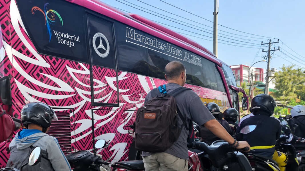 Seorang pria yang dinarasikan sebagai warga asing terlihat menuntun sepeda motor di tengah antrean BBM di Jalan AP Pettarani, Makassar. Identitas dan keterangannya belum terverifikasi